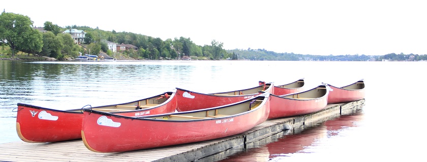 Cinq kayaks sur un quai en bois, au bord de l'eau.